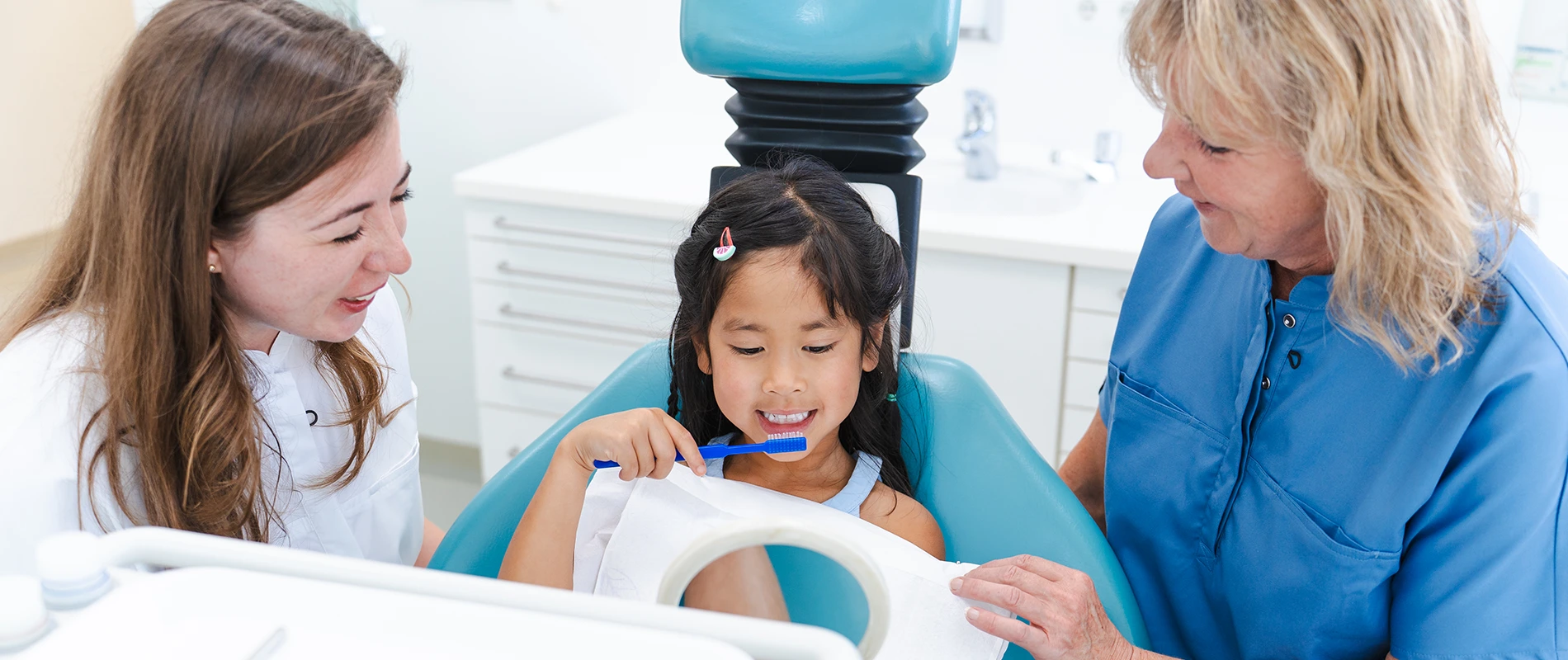 Zahnärztin zeigt Kind die richtige Zahnputztechnik